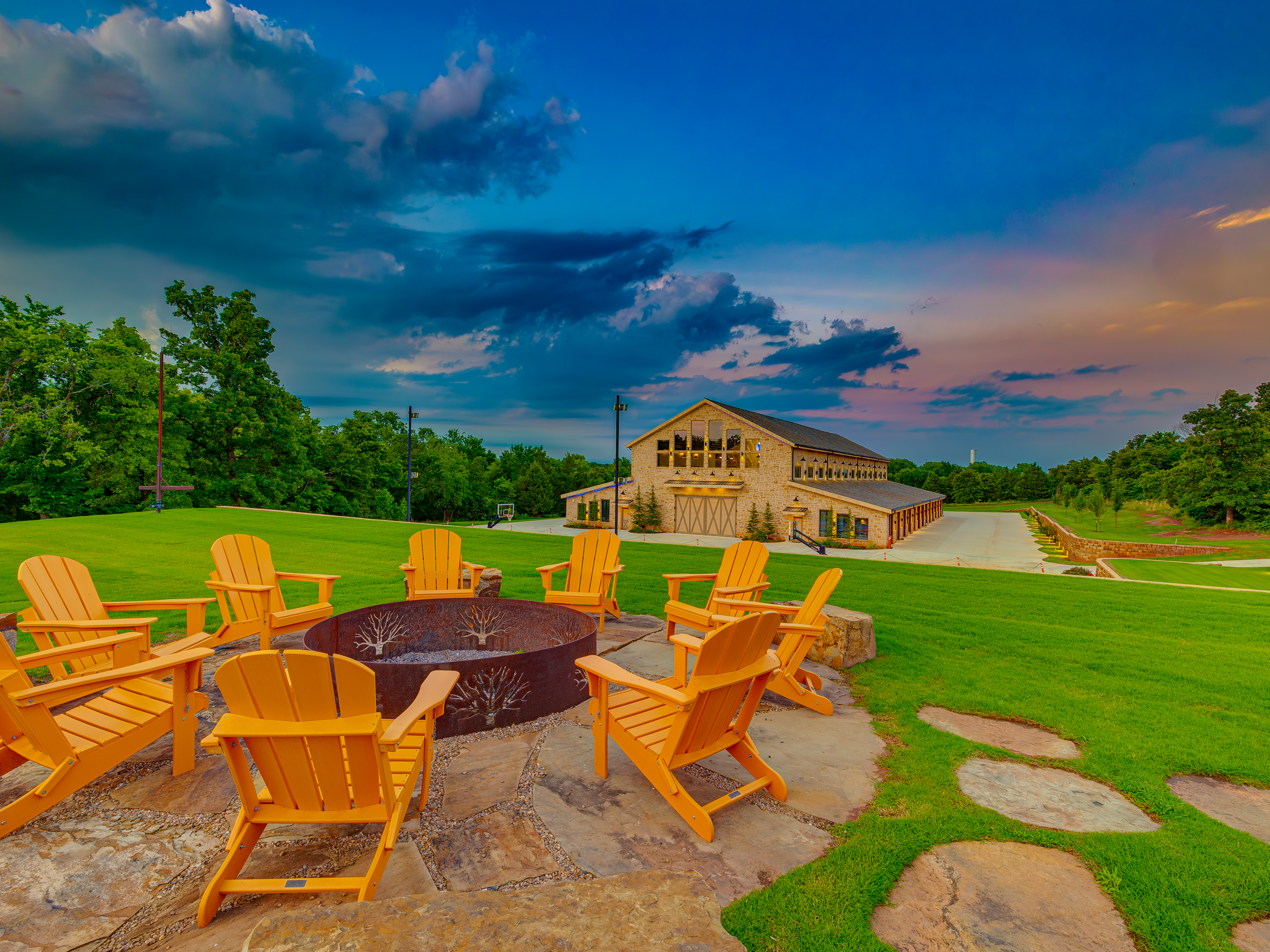 Fire pit with Adirondack chairs and the barn in the background at dusk