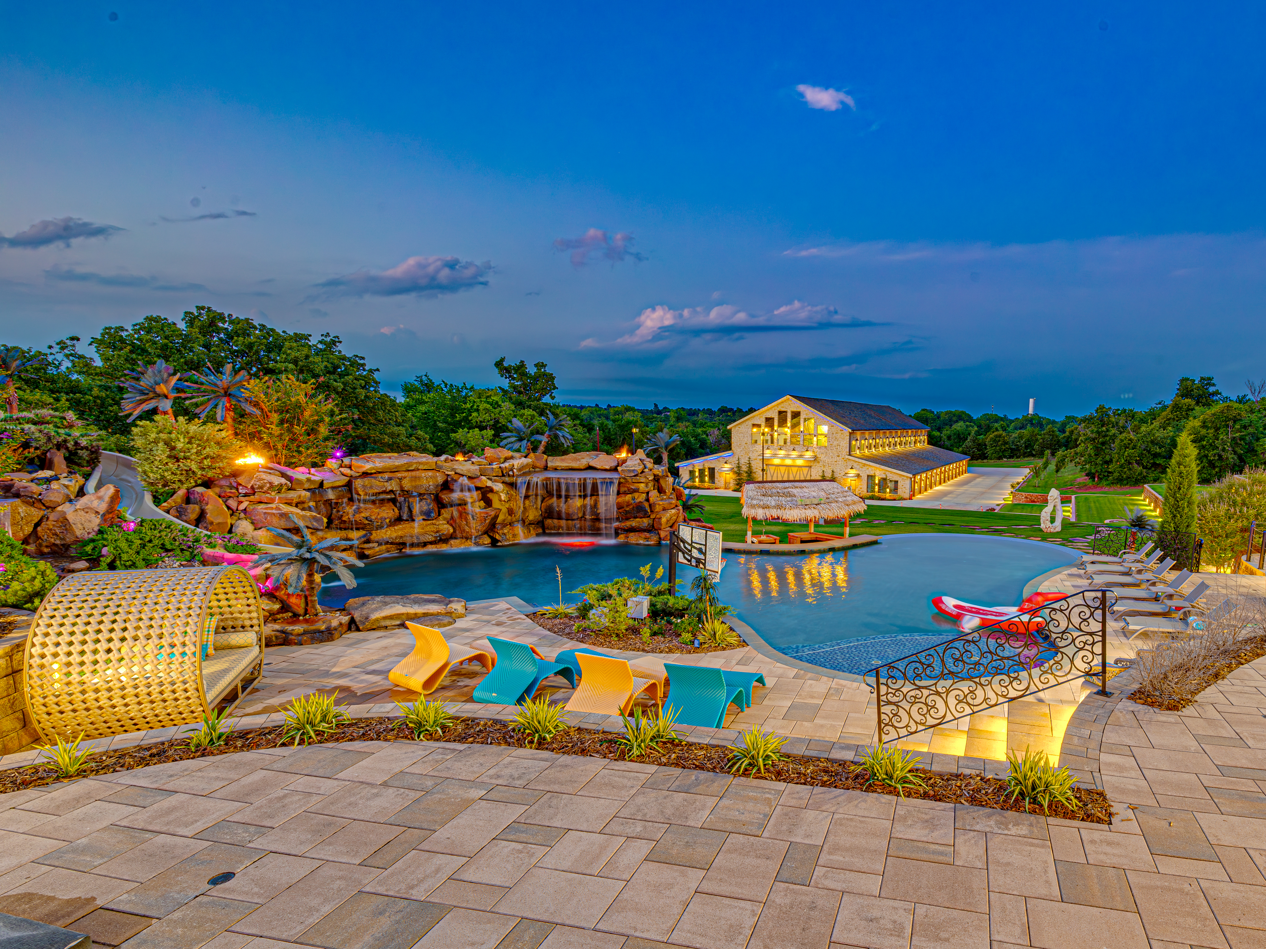 Pool with rock waterfall feature and the barn at twilight